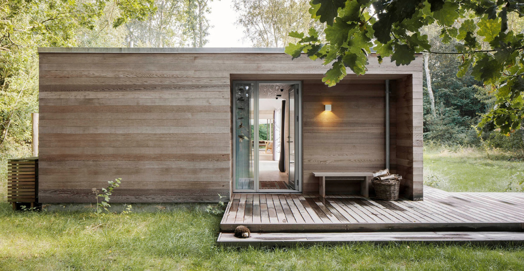 Sommerhus med træfacade, glasdøre og terrasse.
