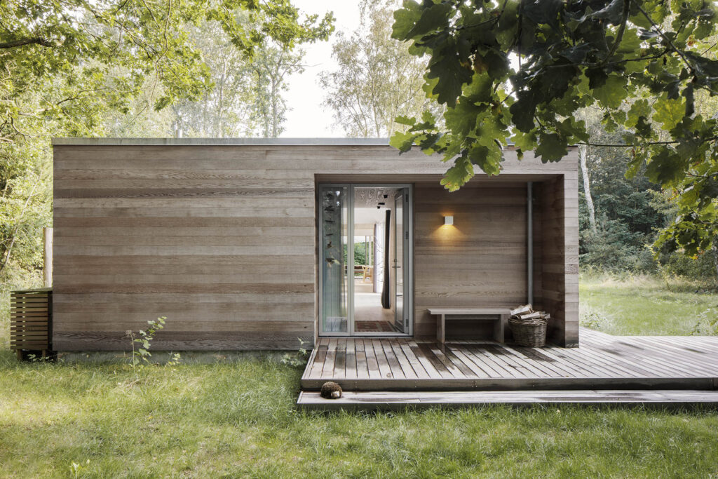 Sommerhus med træfacade og glasdøre ud til en træterrasse.