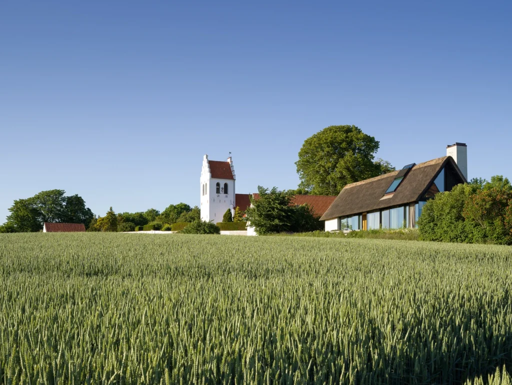 Hvidt hus med tårn ved en græsplæne.